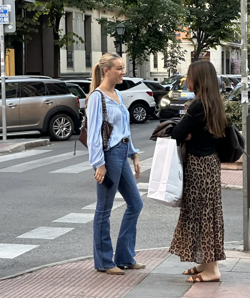 two stylish women chatting on a street corner